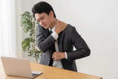 肩周りに不快感を覚えている男性